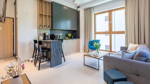 Una sala de estar moderna con un sofá, una mesa de centro y un comedor con sillas, además de una cocina al fondo.