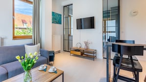 Una sala de estar moderna con un sofá, una mesa de centro y un televisor montado en la pared.
