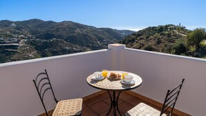 A round table with a tiled top, two chairs, and a breakfast setting with croissants, orange juice, and a cup. - Torrox 006 (Torrox)