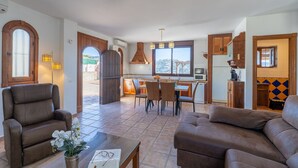A spacious living area with a dining table and chairs, a kitchen with wooden cabinets, and a view of the outdoors. - Torrox 006 (Torrox)