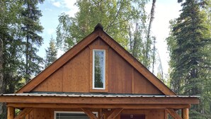 A wooden cabin with a porch, a door marked 'B', and a window. - Moose Landing Cabin C87 with all the amenities (Wasilla)