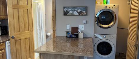 A compact laundry room with a washing machine, a dryer, and a small countertop with toiletries.