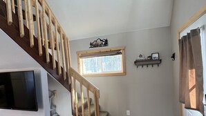 A staircase with wooden railings leading to a landing with a window and wall-mounted decor. - Moose Landing Cabin C87 with all the amenities (Wasilla)