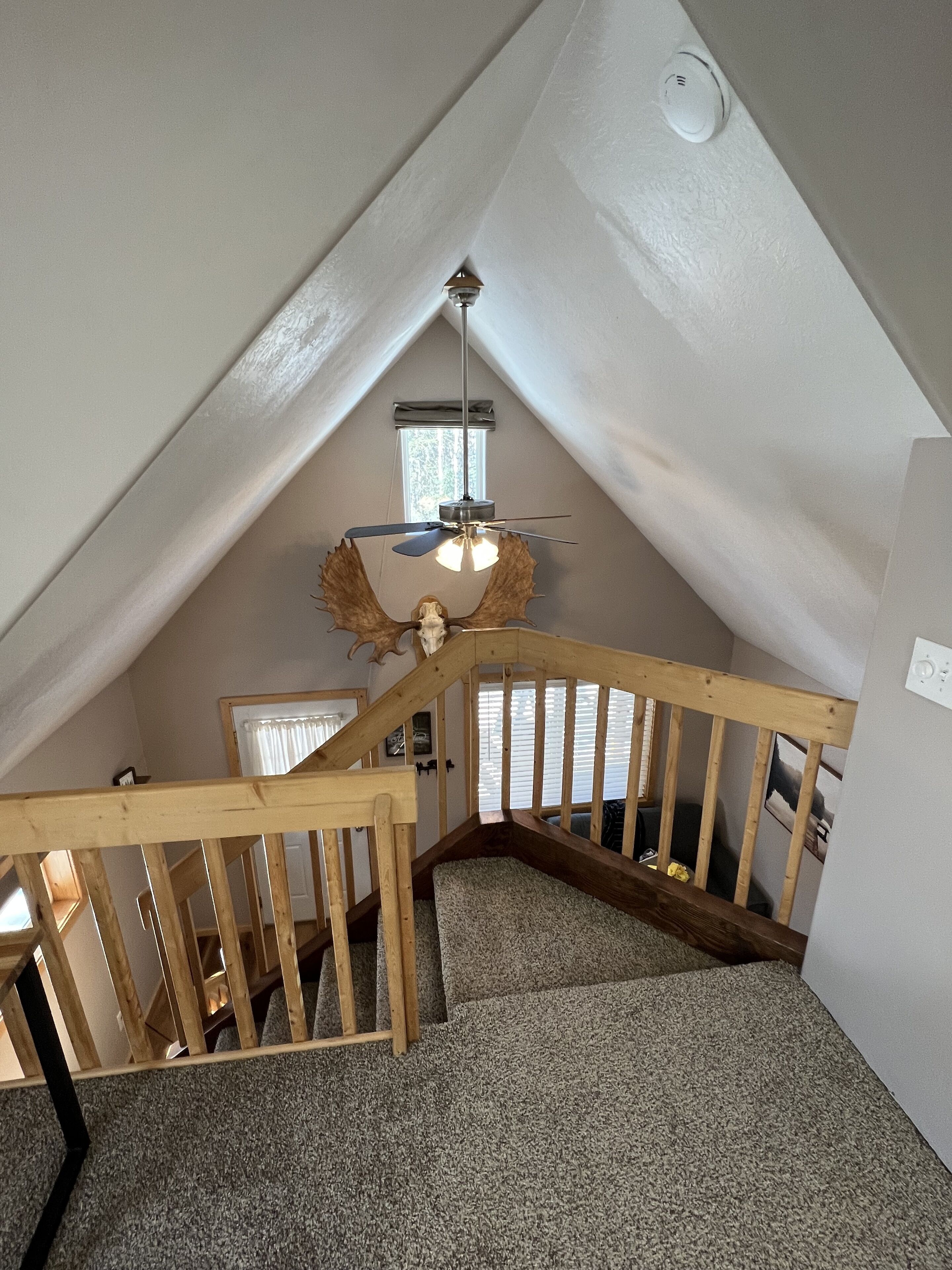 Un escalier en bois et un ventilateur de plafond dans une pièce aménagée dans un style industriel.