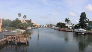 A calm river with a wooden dock and a boat docked on the right. - Satellite Motel - The Hideaway 125 (Treasure Island)
