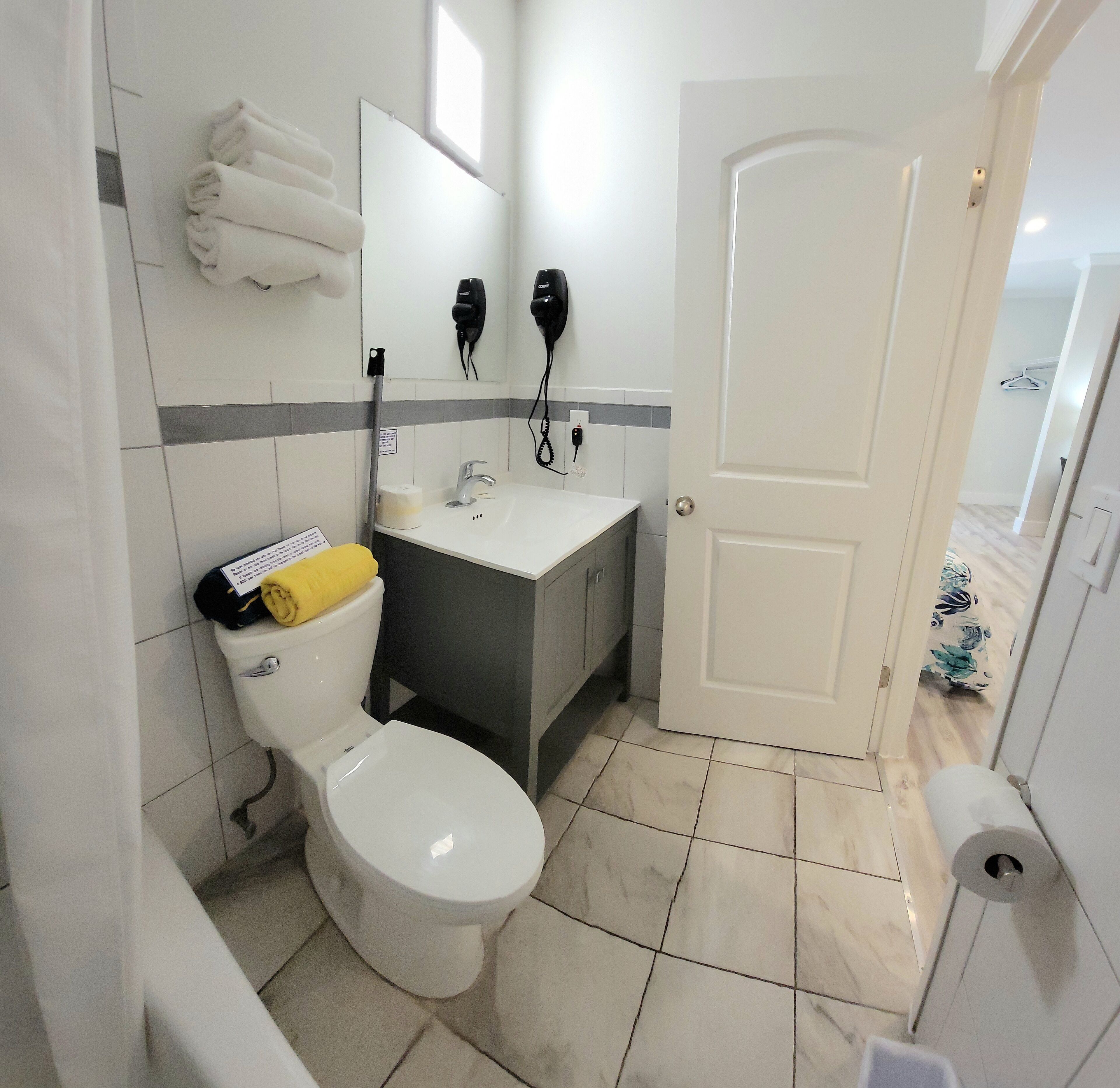 A bathroom with a toilet, sink, and hairdryer.