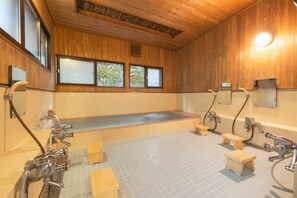 Ein Holzinterieur mit einer großen Badewanne, zwei Waschbecken und Holzschemeln.