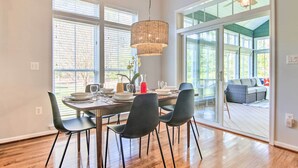 Spiseområde med et bord dækket til fire personer, store vinduer og udsigt til en terrasse.