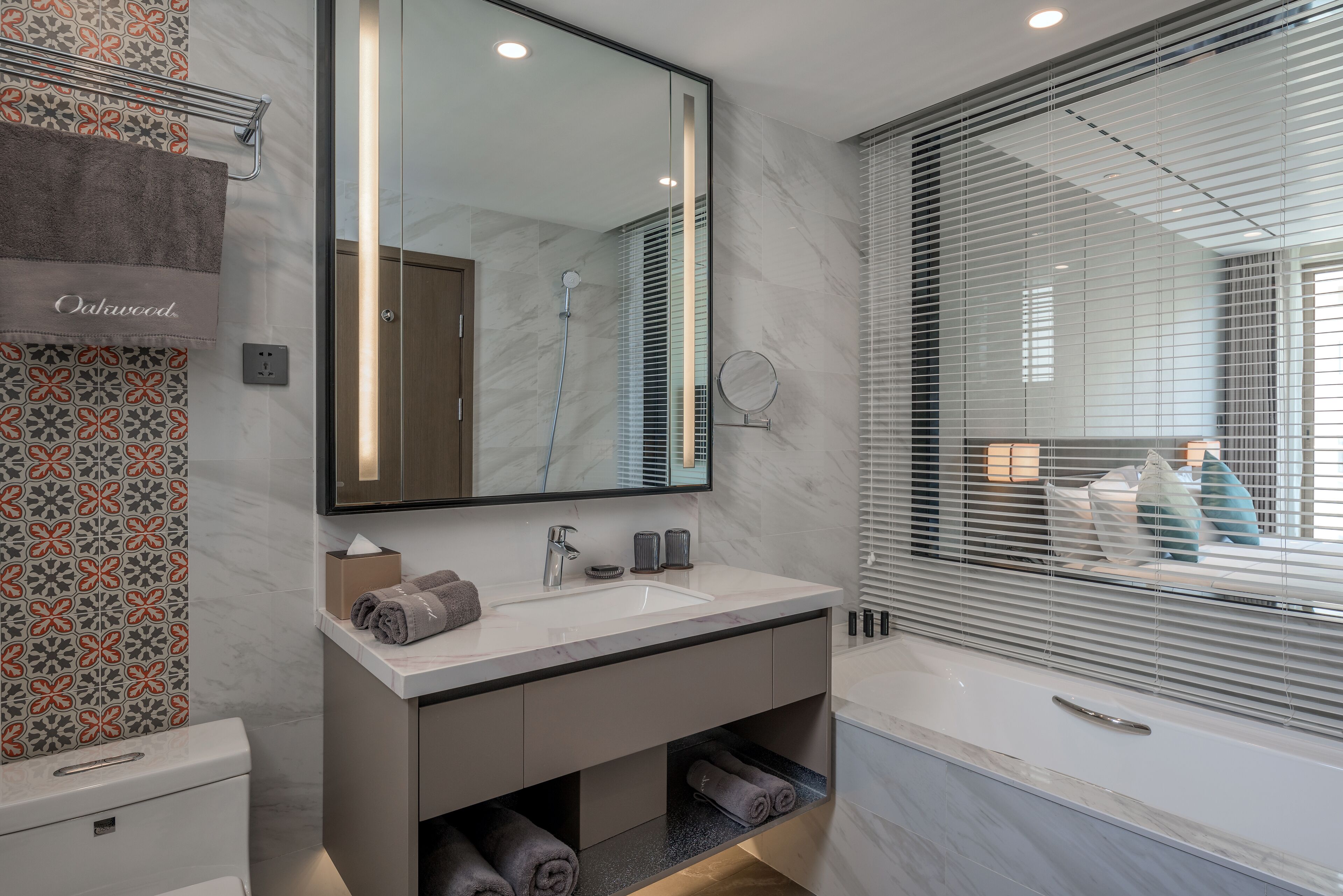 A modern bathroom with a large mirror, a sink, and a bathtub.