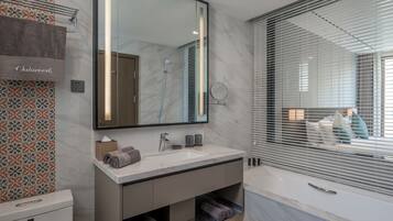 A modern bathroom with a large mirror, a sink, and a bathtub.