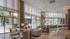 Een ruime lobby met grote ramen, comfortabele zitplaatsen en decoratieve elementen.