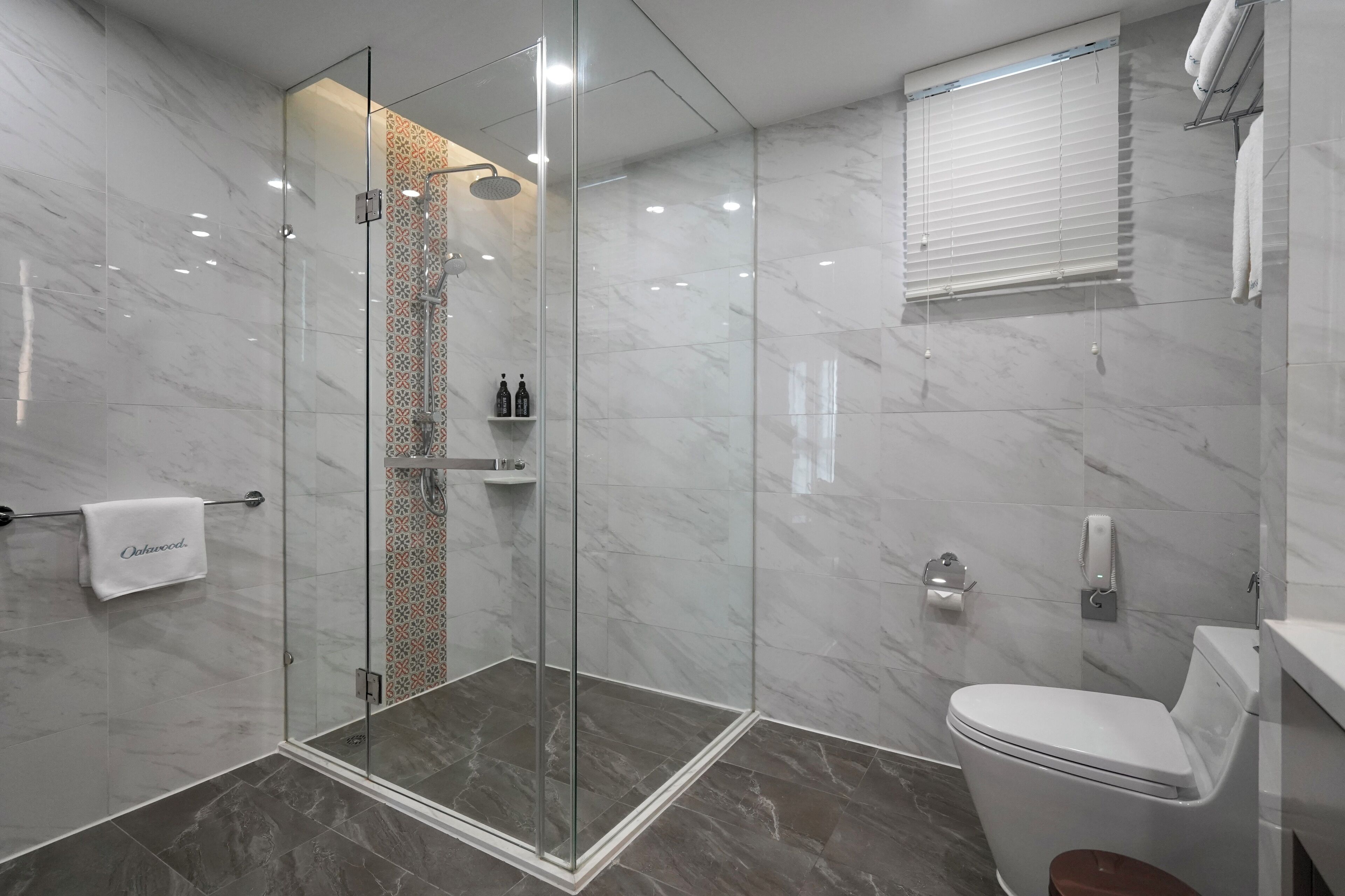 Un baño moderno con ducha de vidrio, inodoro y toallero.