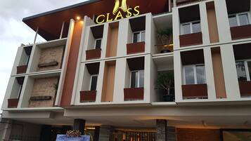 Ein mehrstöckiges Hotel mit Balkonen, einem Schild mit der Aufschrift „CLASS“ und einer Werbetafel für ein Gästehaus.