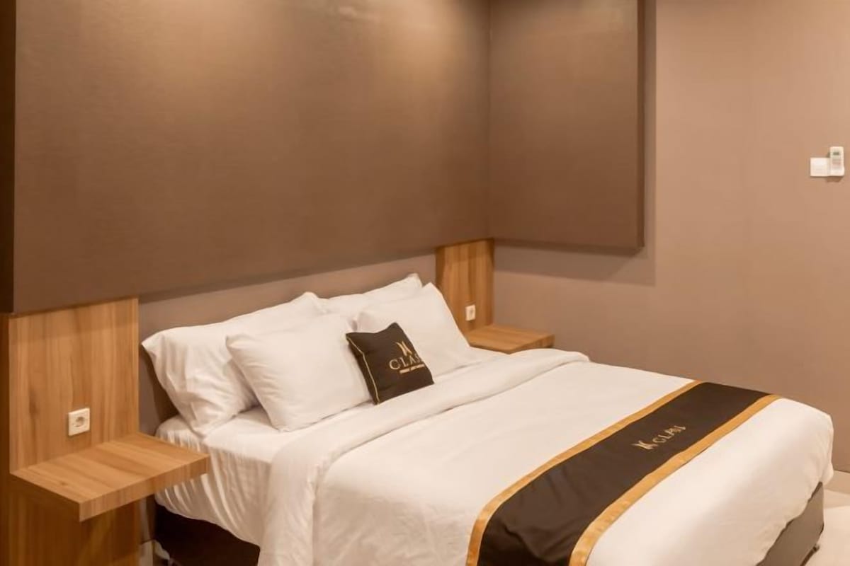 Una camera d'albergo con un letto, una testiera in legno, comodini e un lampadario a parete.