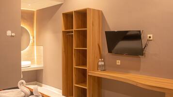 Ein Hotelzimmer mit einem Bett, einem an der Wand montierten Fernseher, einem Holzschrank und einer Klimaanlage.