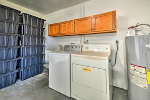 Compact laundry room with a washing machine and dryer, along with storage bins and cabinets.