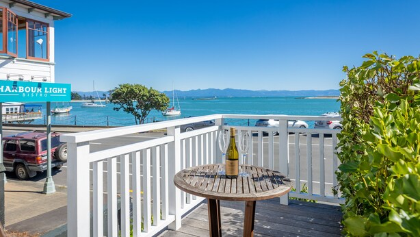 Un balcon avec une table, une bouteille de vin et une vue sur la mer et les bateaux.