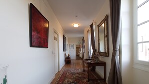 Un couloir agrémenté d’un tapis à motifs, d’une console en bois et d’un grand miroir.