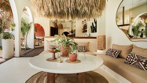 A modern living room with a round white table, a sofa with patterned cushions, and a large mirror reflecting the space. - Stunning 4BR Villa With Rice Field View in Umalas (Kerobokan)