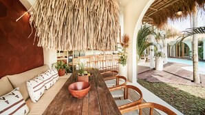 A dining area with a wooden table, wicker chairs, and a hanging thatch ceiling. - Stunning 4BR Villa With Rice Field View in Umalas (Kerobokan)