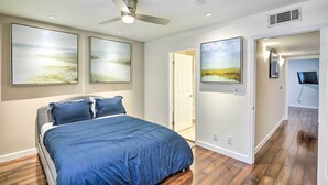 Ein Schlafzimmer mit einem Bett, einem Deckenventilator und drei Landschaftsbildern an der Wand.