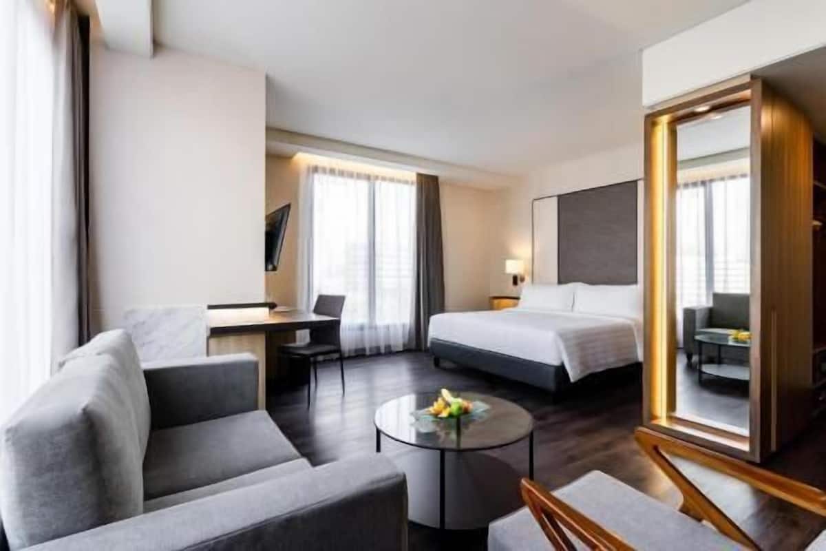 Una habitación de hotel con una cama, un escritorio, una silla, una mesita de centro redonda y un espejo grande.