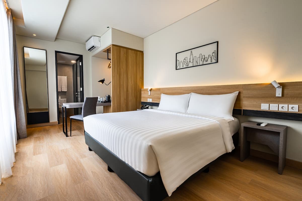Una habitación de hotel con una cama grande, mesitas de noche, un escritorio y una silla.