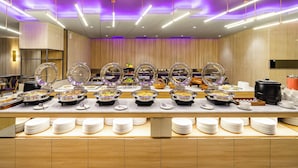 A buffet setup with multiple food stations, including hot and cold dishes, and a variety of serving utensils. - Quest Prime Pemuda - Semarang (Semarang)