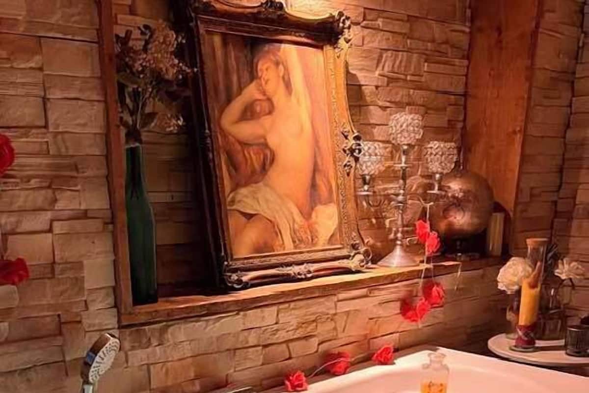 Uma banheira de hidromassagem com água corrente, cercada por paredes de pedra e uma pintura.
