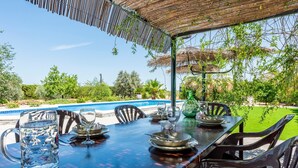 Mesa de comedor al aire libre, con piscina al fondo.