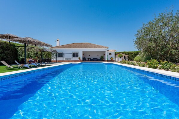 Une piscine avec des chaises longues et un espace de repos abrité.