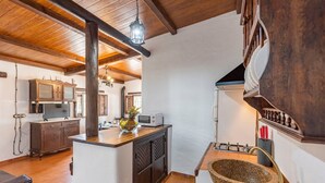 A rustic kitchen with wooden beams, a stone sink, and a microwave on the counter. - Holiday Home 'Rural El Ventorrillo' with Pool & Wi-Fi (Morón de la Frontera)