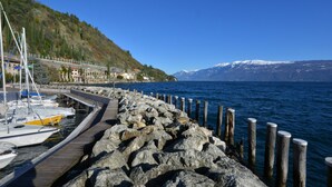 Une jetée rocheuse où sont amarrés des bateaux, un ciel bleu dégagé et un paysage montagneux en arrière-plan.