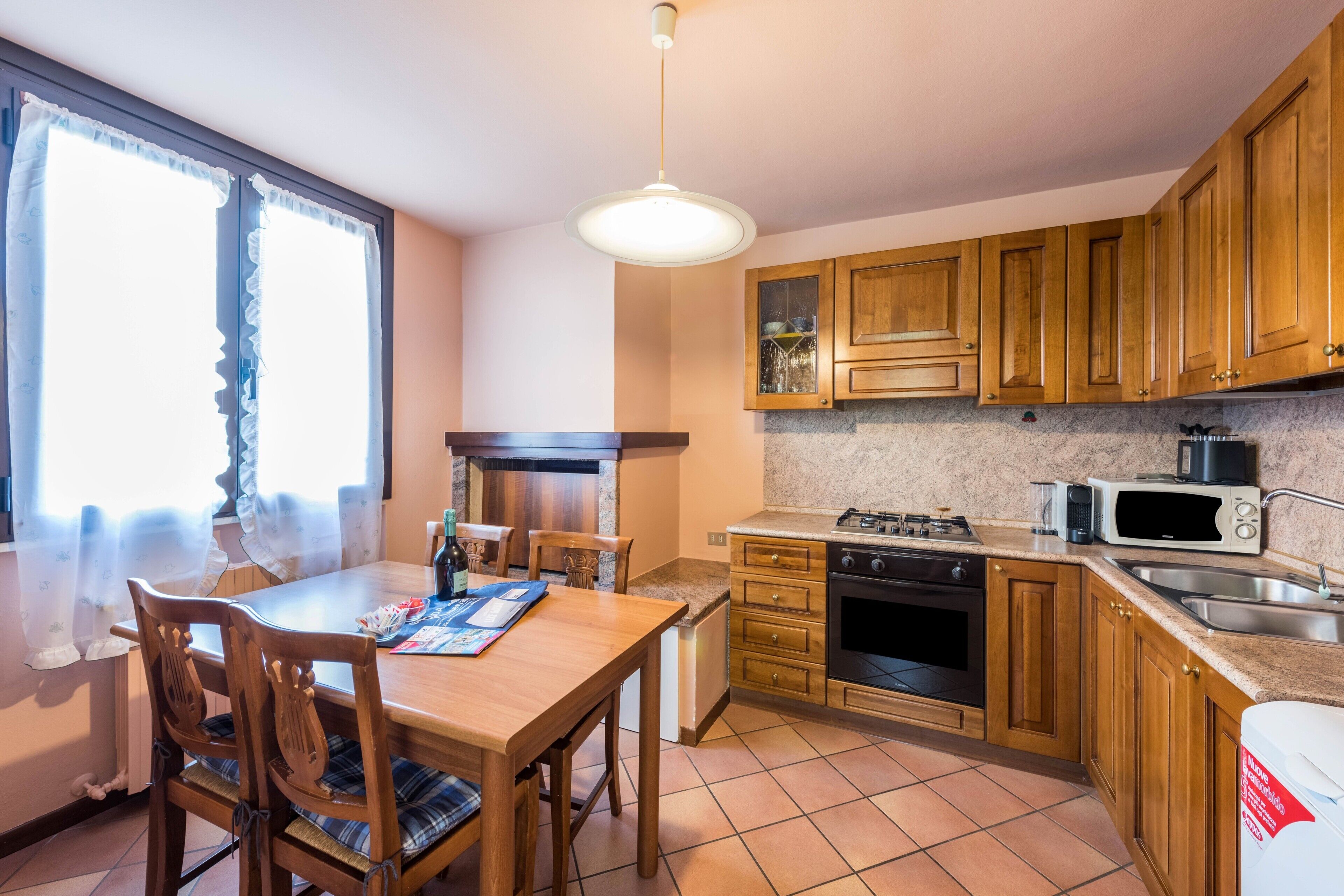 A kitchen with wooden cabinets, a gas stove, a microwave, and a sink.