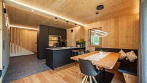 Eine moderne Küche mit Holzwänden, einer zentralen Kochinsel und einem Essbereich mit Tisch und Stühlen.