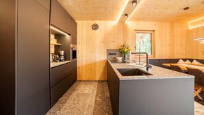 Eine moderne Küche mit Holzwänden, einem Einbauofen, einem Spülbecken und einem Essbereich mit einer Bank.