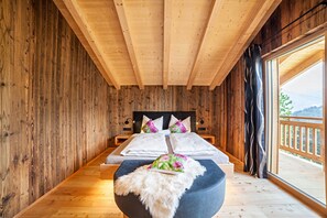 Een houten kamer met een bed en uitzicht op de natuur, met een groot raam.