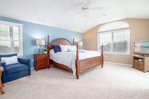A bedroom with a large bed, two bedside tables, a dresser, a television, and a ceiling fan. - Saltwater Haven - Walkable Shore Stay (Avalon)