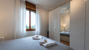 Habitación de hotel con una cama grande, un armario, un espejo y una ventana con cortinas.