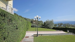 Un área ajardinada con un farol, escalones y un edificio al fondo.