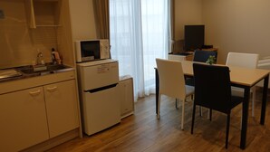 Eine kleine Küche mit Mikrowelle, Kühlschrank und Spüle. Ein Essbereich mit Tisch und Stühlen vorhanden.