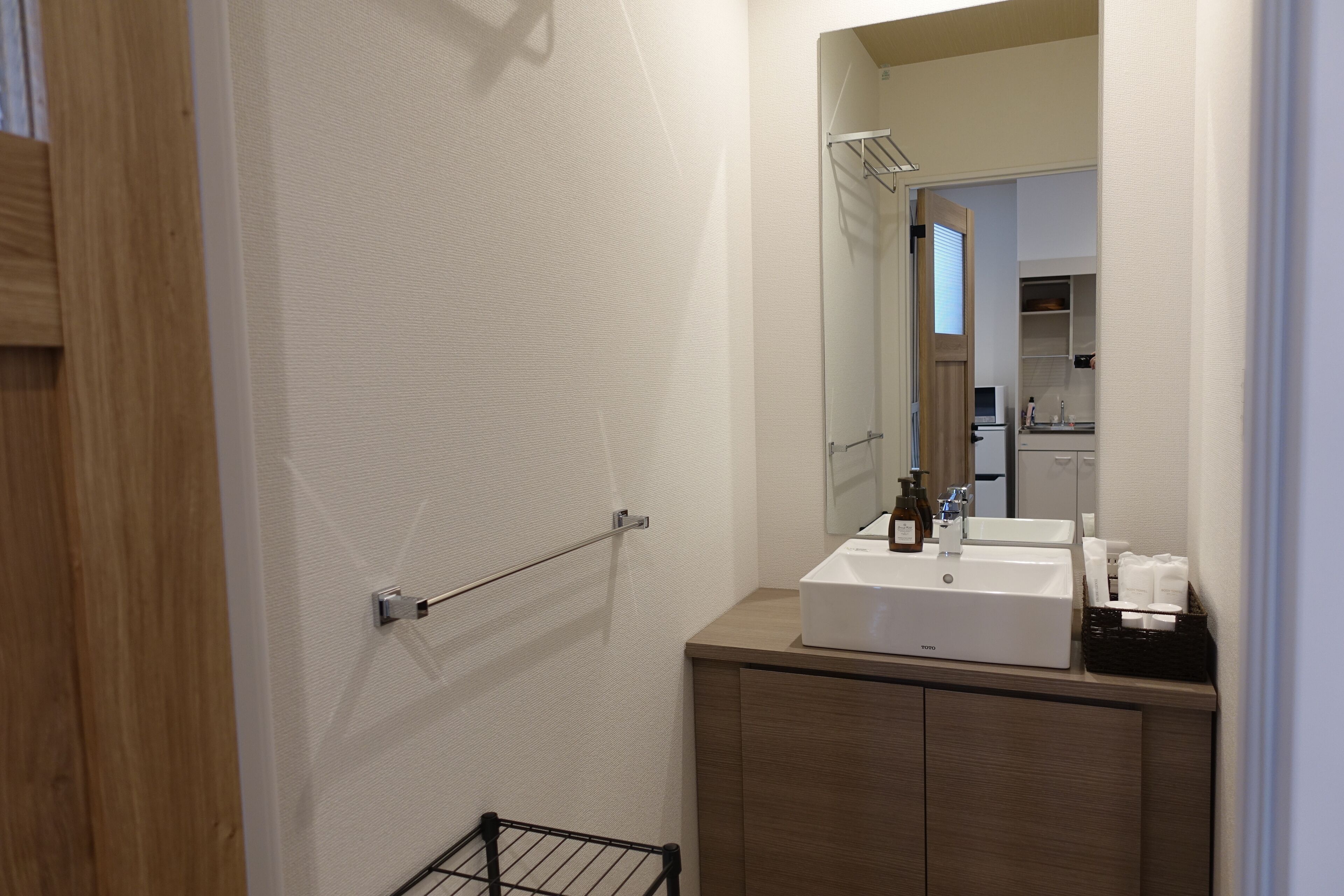 Un baño moderno con tocador de madera, un espejo grande y un lavabo blanco.
