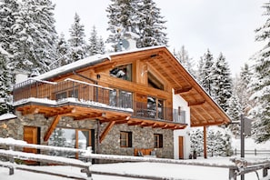 A wooden chalet with a balcony, stone walls, and a ski lift in the background. - High Luxury Chalet "K Lodge Mountain" with Mountain View, Whirlpool and Sauna (Olang)