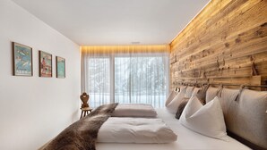 A bedroom with a large bed, a wooden headboard, a window with sheer curtains, and three framed posters on the wall. - High Luxury Chalet "K Lodge Mountain" with Mountain View, Whirlpool and Sauna (Olang)