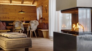 A cozy room with a fireplace, wooden furniture, and a bench. - High Luxury Chalet "K Lodge Mountain" with Mountain View, Whirlpool and Sauna (Olang)