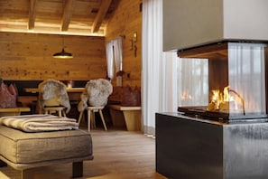 A cozy room with a fireplace, wooden furniture, and a bench. - High Luxury Chalet "K Lodge Mountain" with Mountain View, Whirlpool and Sauna (Olang)
