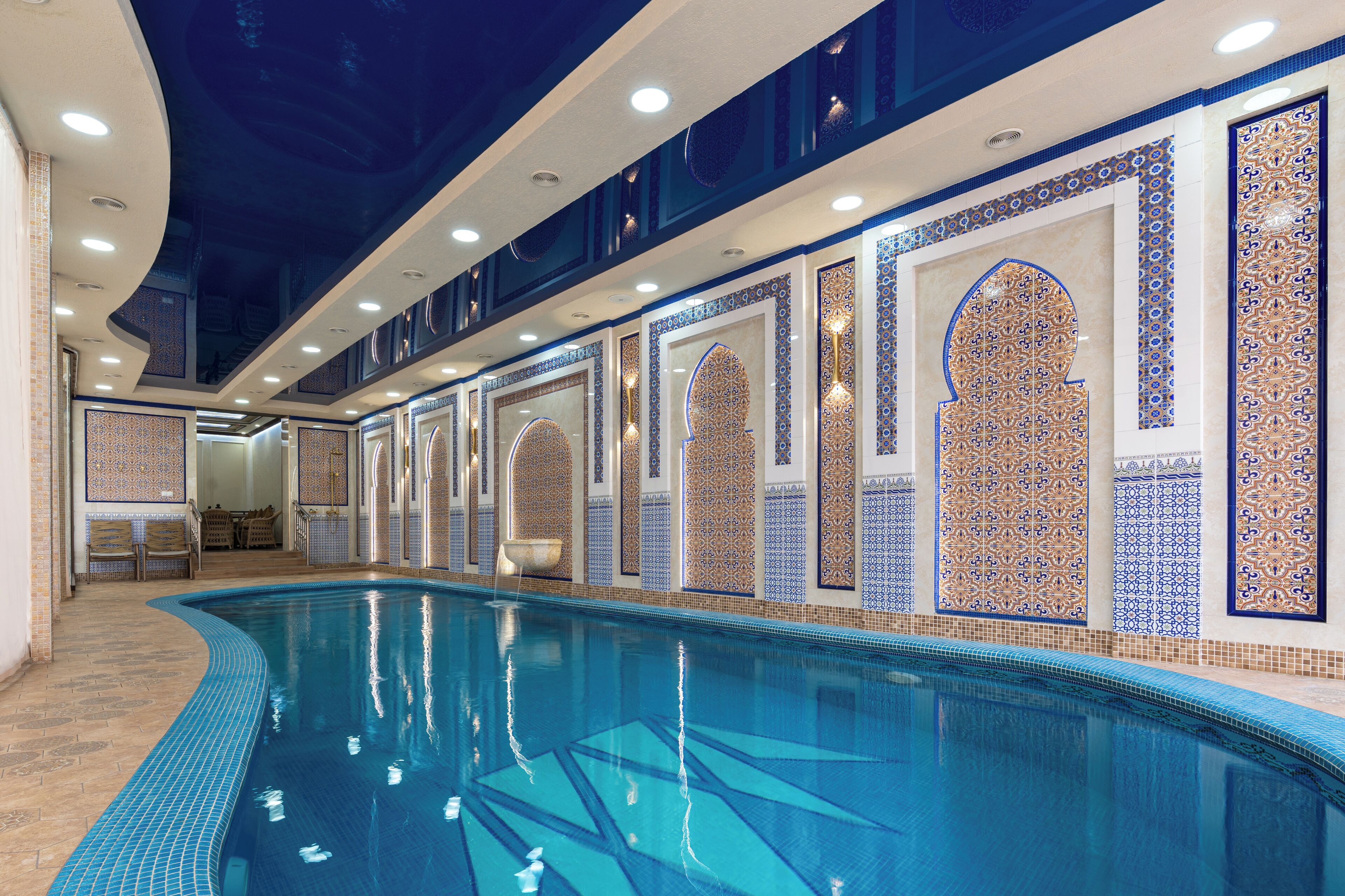 A swimming pool with tiled walls and a ceiling with recessed lighting.