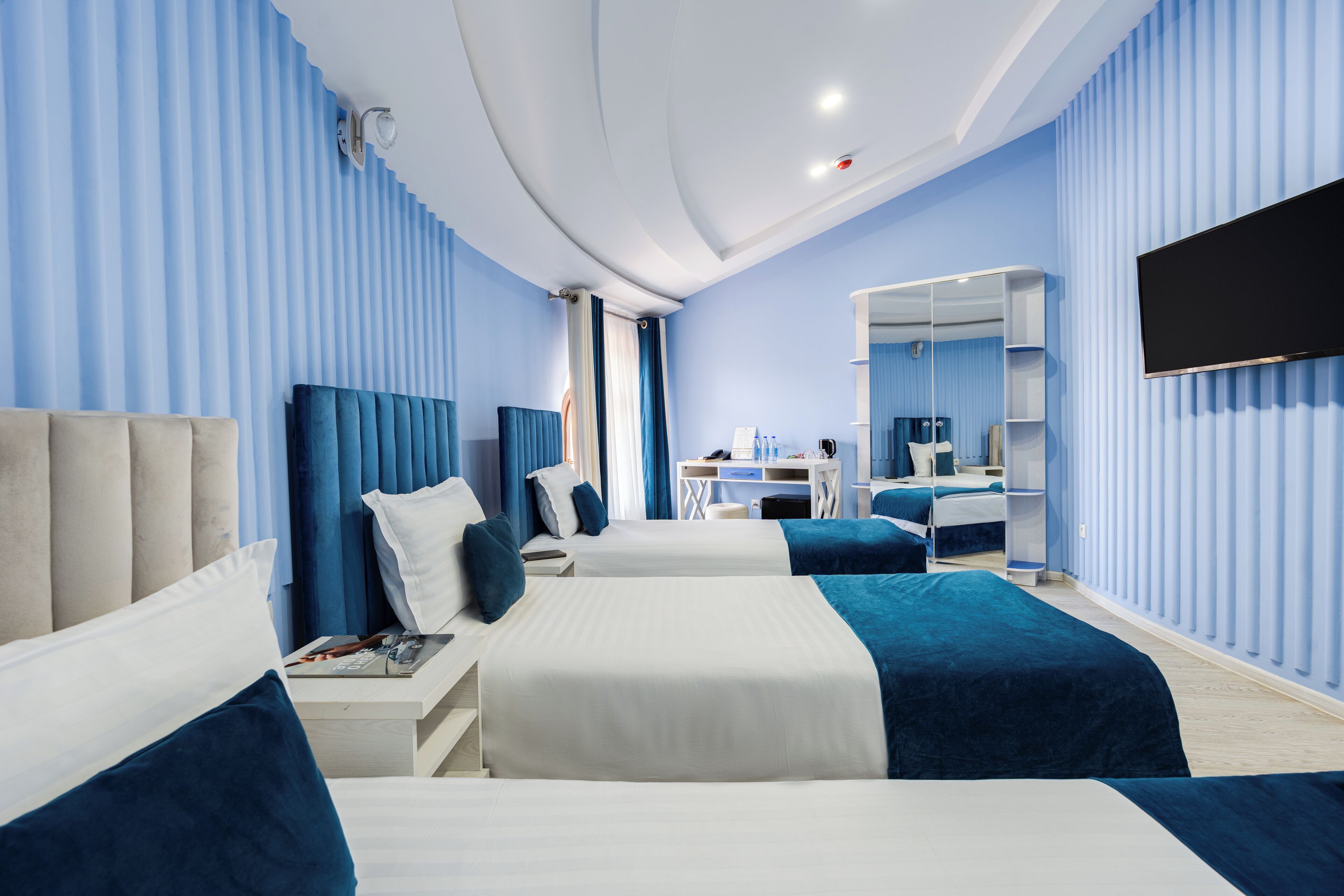 Een hotelkamer met twee bedden, een bureau, een stoel, een televisie en een spiegel.