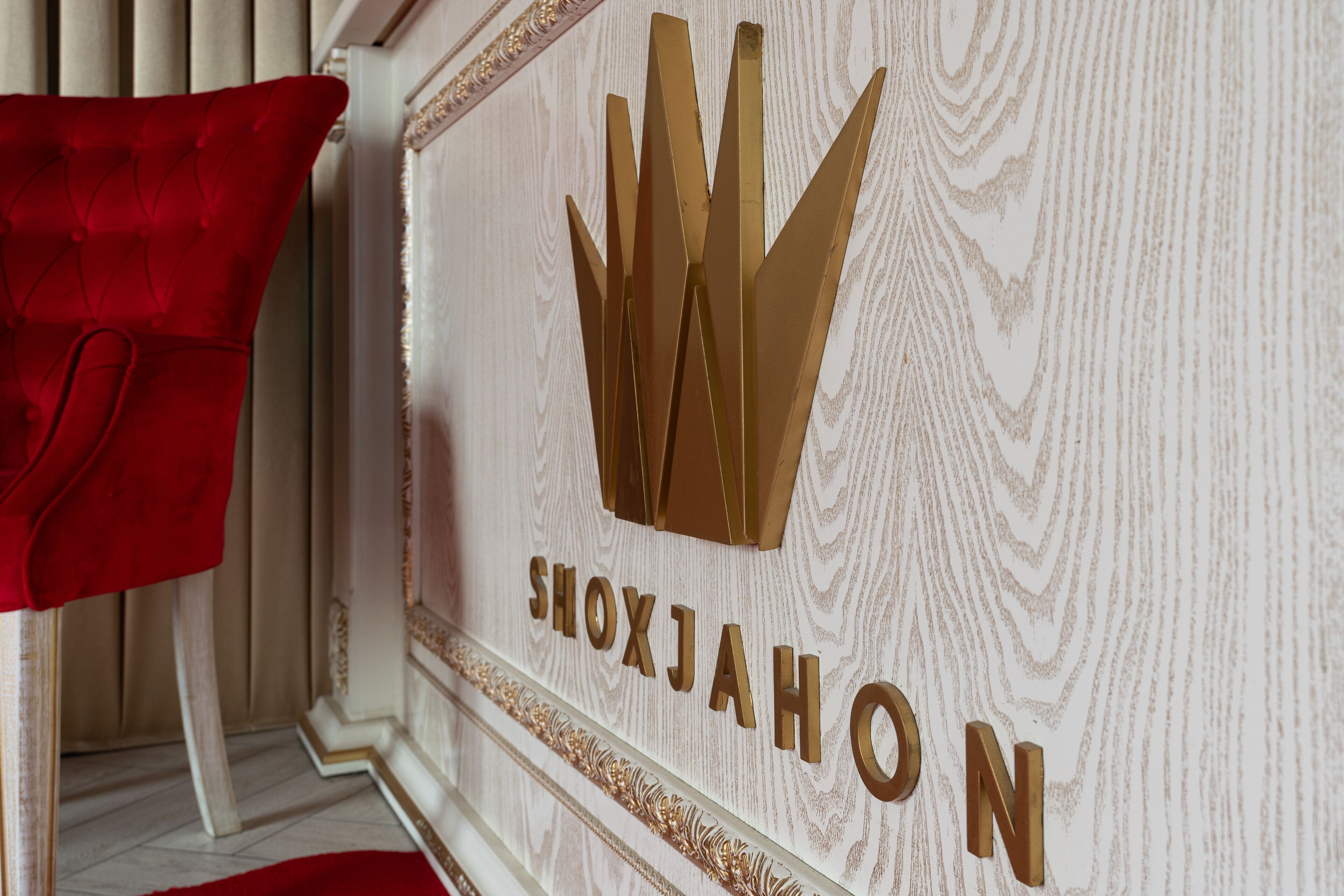 A wall with the text "SHOXJAHON" and a golden crown symbol.