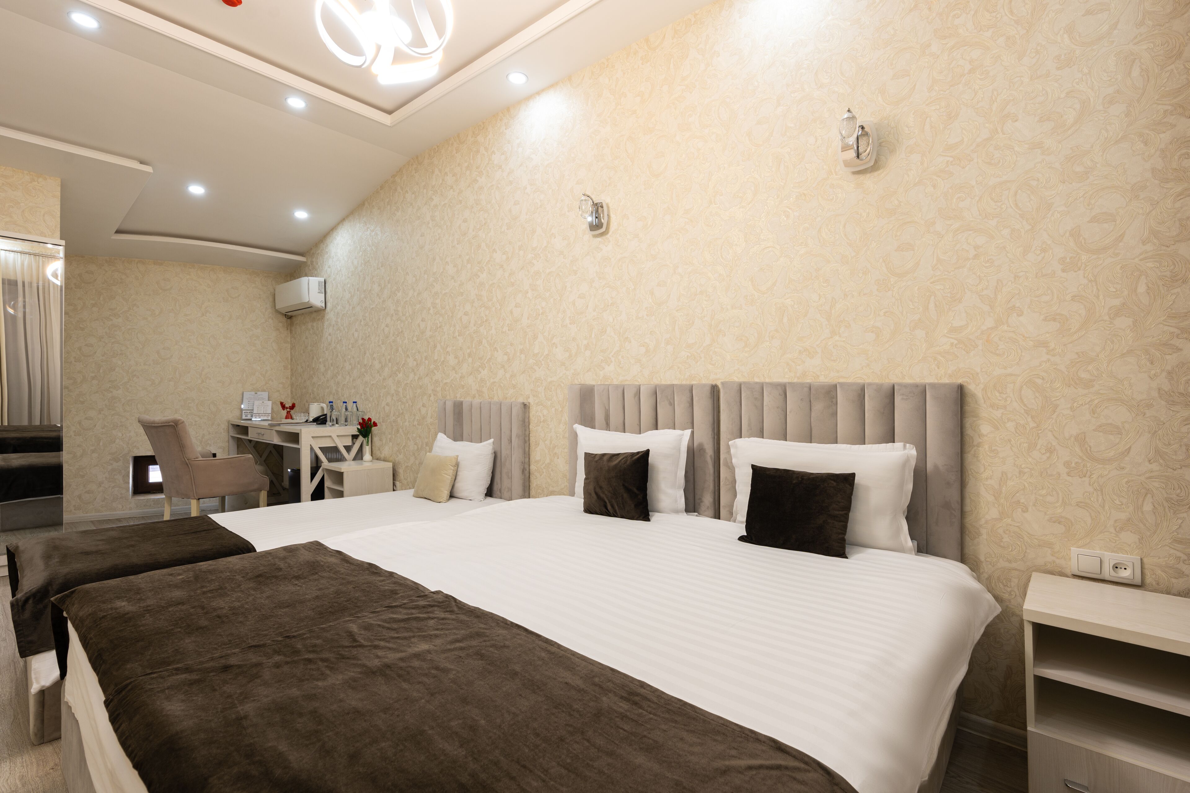 A hotel room with a large bed, a desk, and a chair.